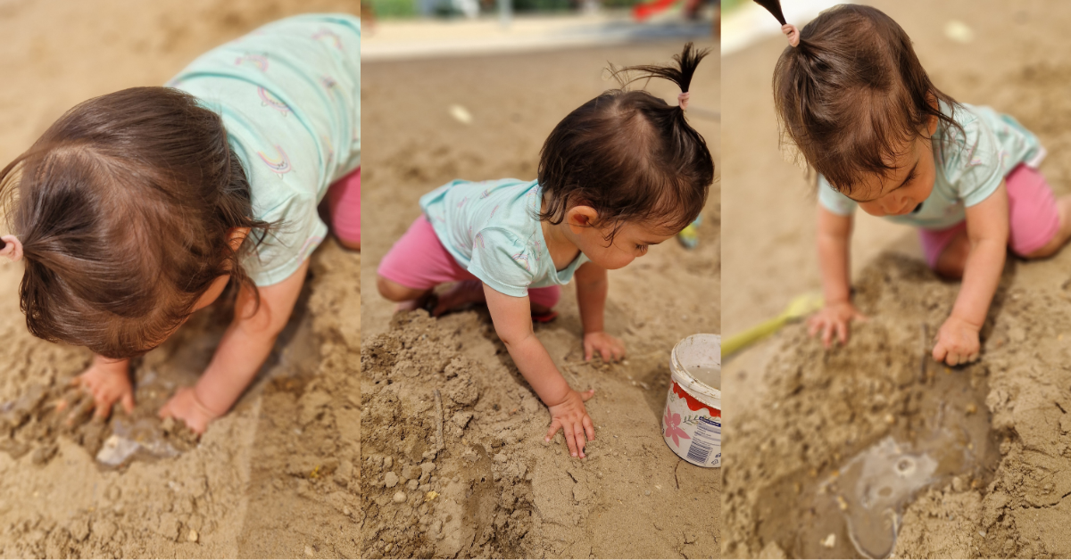 A toddler playing in a sandpit, pressing both hands into the sand and exploring the texture — one of the simplest and most absorbing toddler learning activities for children under 2.