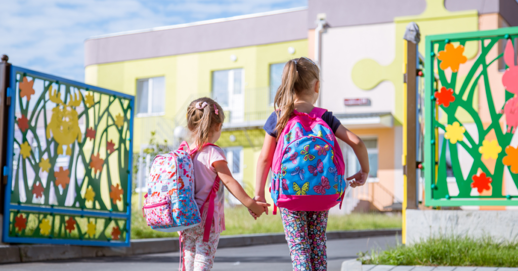 Two girls walking to school wearing colorful kids backpacks for school