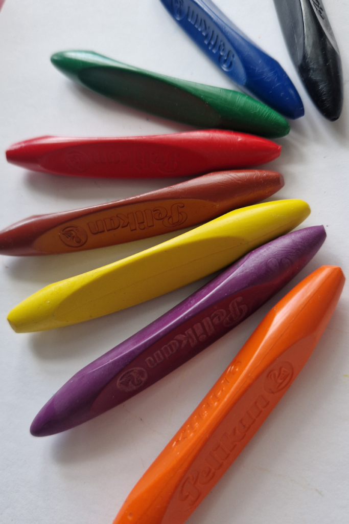 Pelikan crayons in multiple colors laid out on a white surface, showing the smooth wax texture and vivid pigment of quality crayons for kids