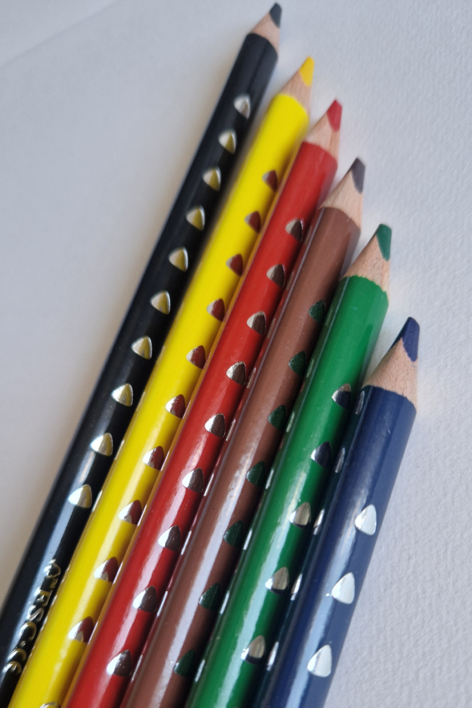 Jumbo triangular colored pencils in multiple colors arranged in a fan shape, showing the ergonomic three-sided barrel designed to support a natural grip for young children