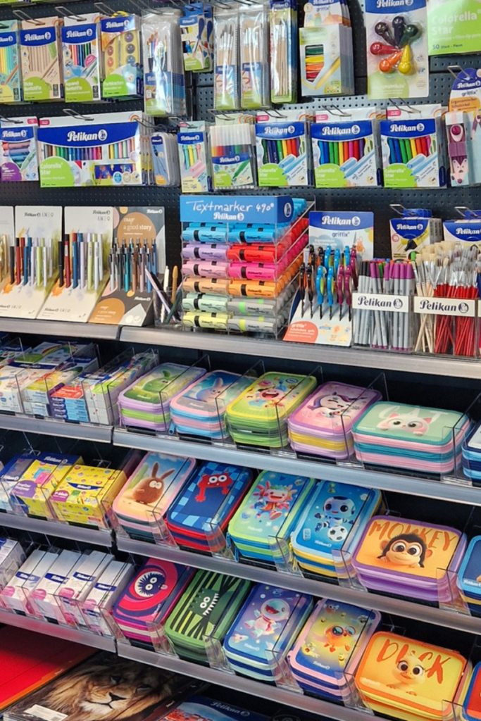 A store shelf filled with colorful pencils, markers, pens, and pencil cases, the kind of variety parents face when shopping from an elementary school supplies list