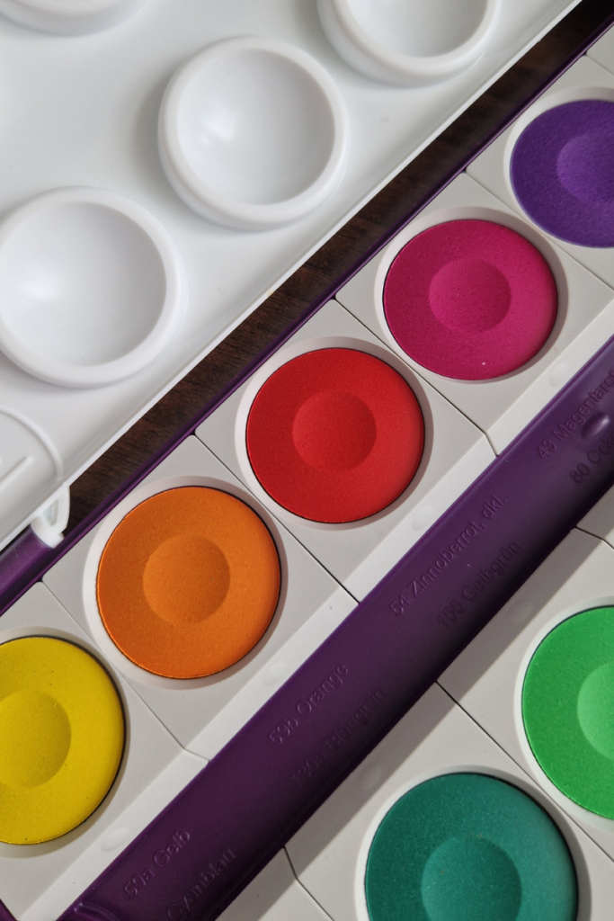 A watercolor paint set with large vivid color pans seen from above, showing the rich pigment and generous pan size ideal for kids